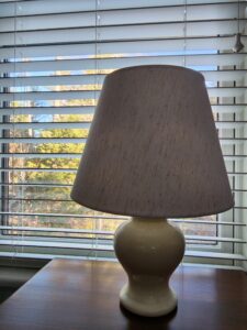 Photo of a desk lamp set against a shuttered window.