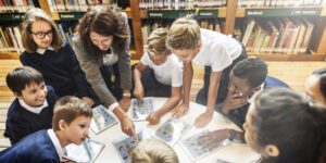 Photo of a teacher reviewing material with students in a library.