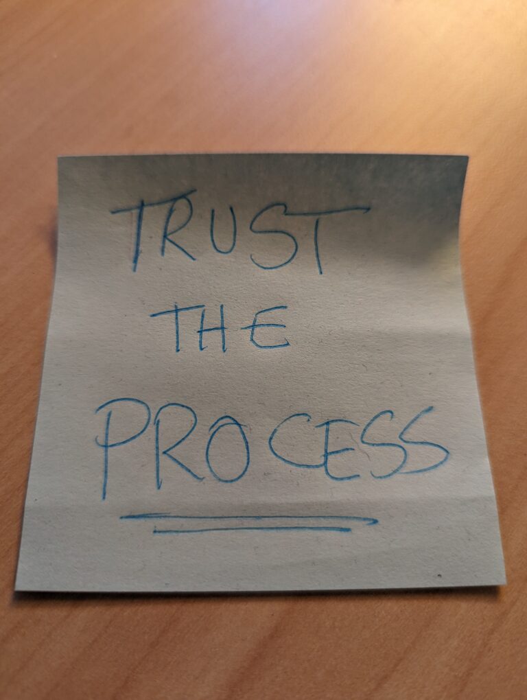 Photo of a sticky note that reads "Trust the process".