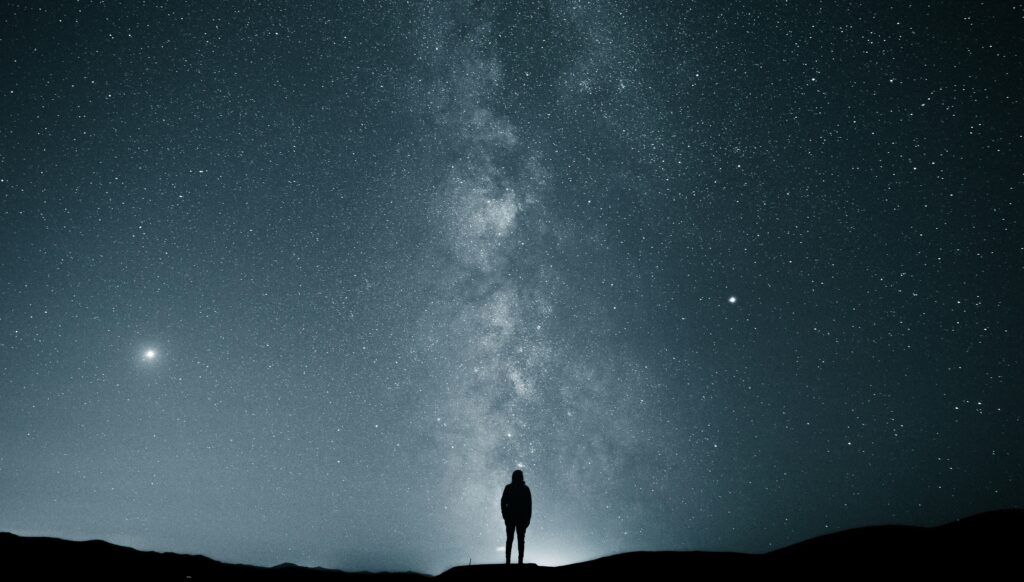Image of a person looking up at a star filled sky.